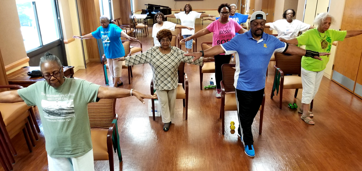 Group of seniors with arms stretched out doing a falls prevention exercise