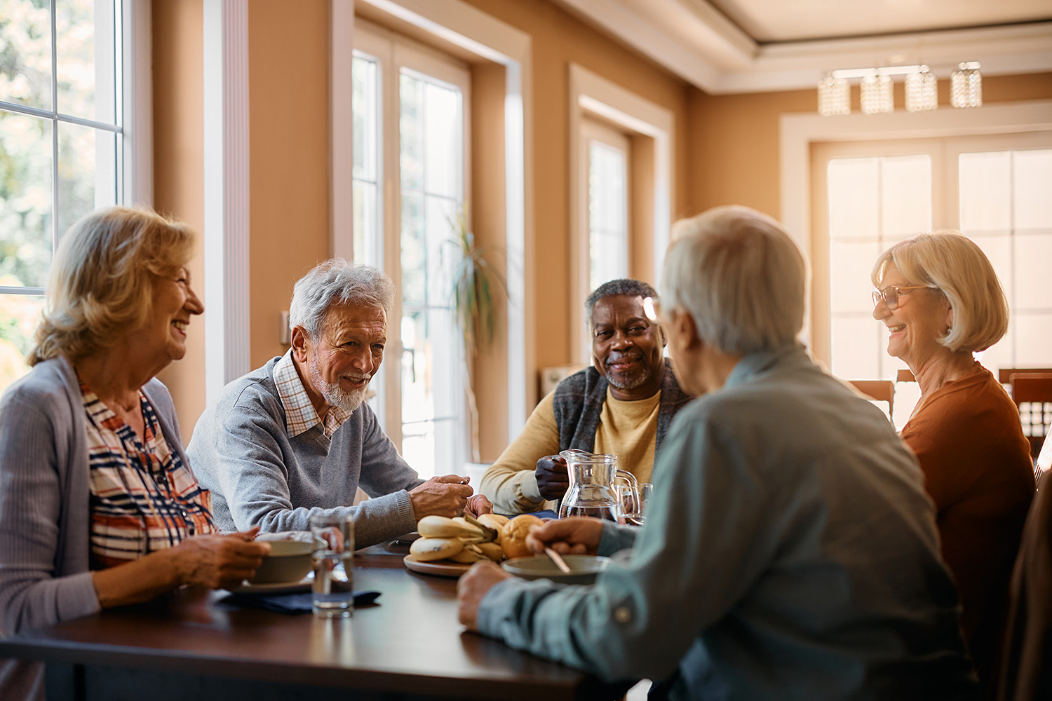 five people gathered at a table eating