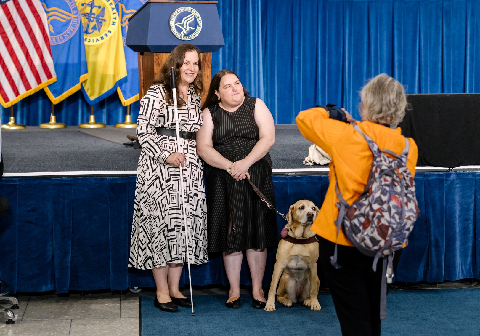 Two women and a service dog pose for a photo at the ADA 35th Anniversary event