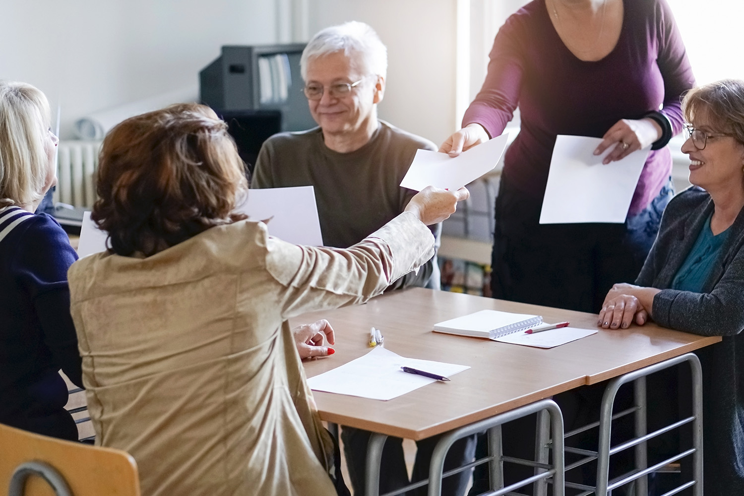 a table of four with a woman handing a paper to another woman