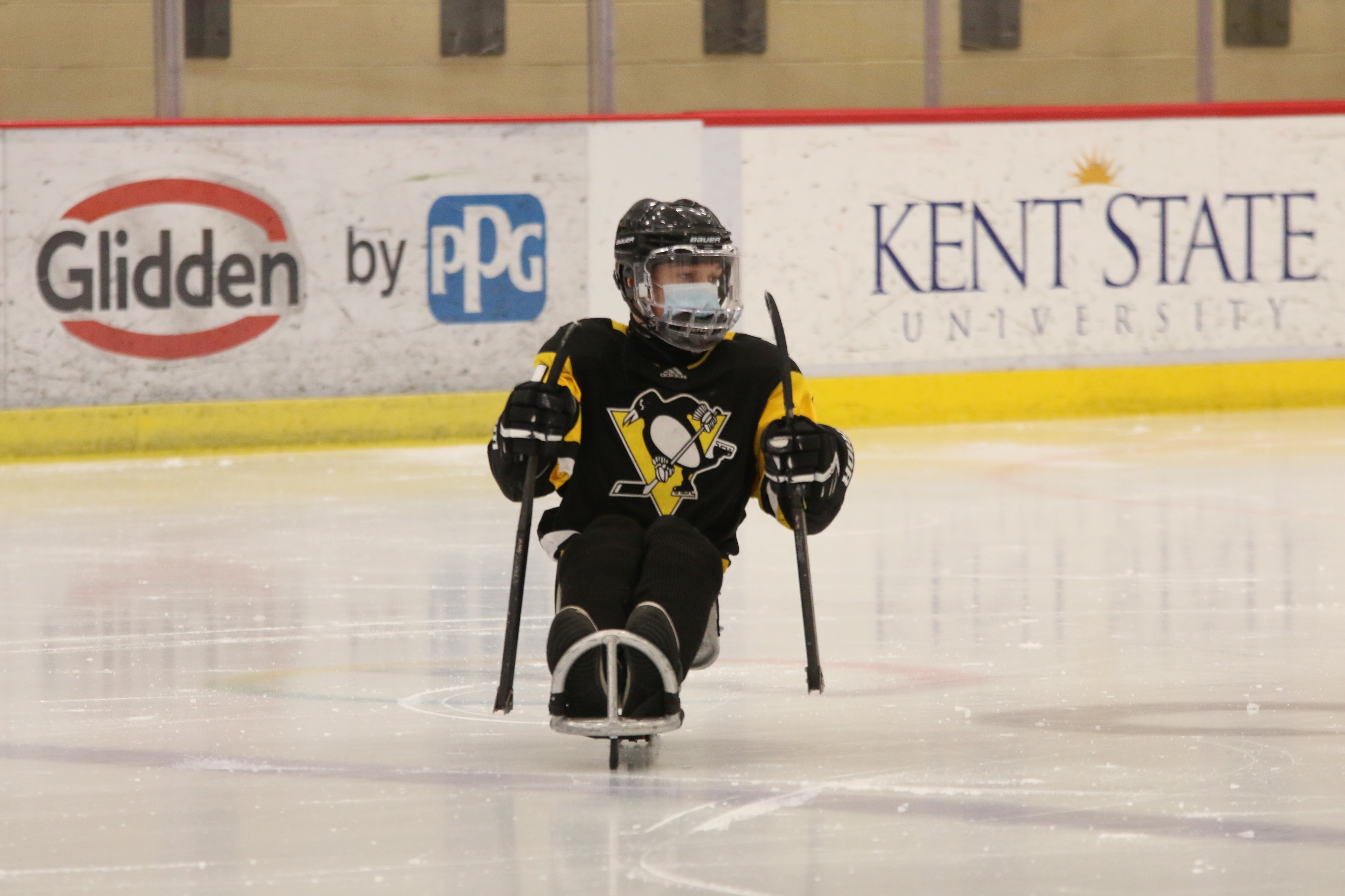 A player propels themself across the ice on a hockey sled