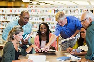 Diverse group of older and younger adults working in library