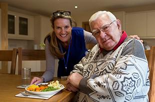 Woman serving meal to older man at home